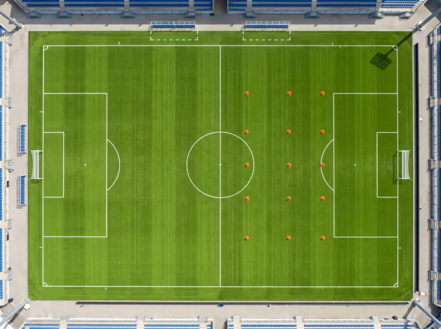 Campo de futbol visto desde arriba con lineas tacticas superpuestas sobre el cesped verde